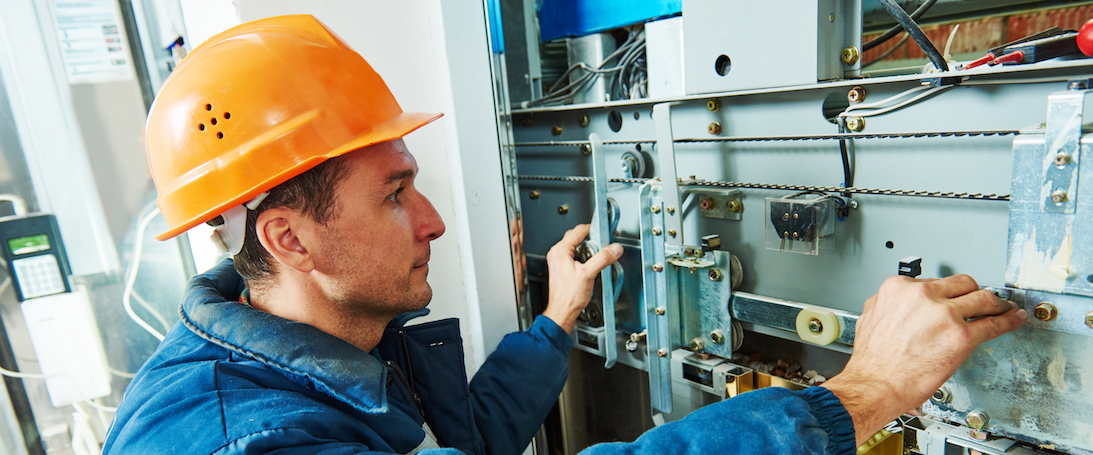 technician worker adjusting elevator mechanism of lift